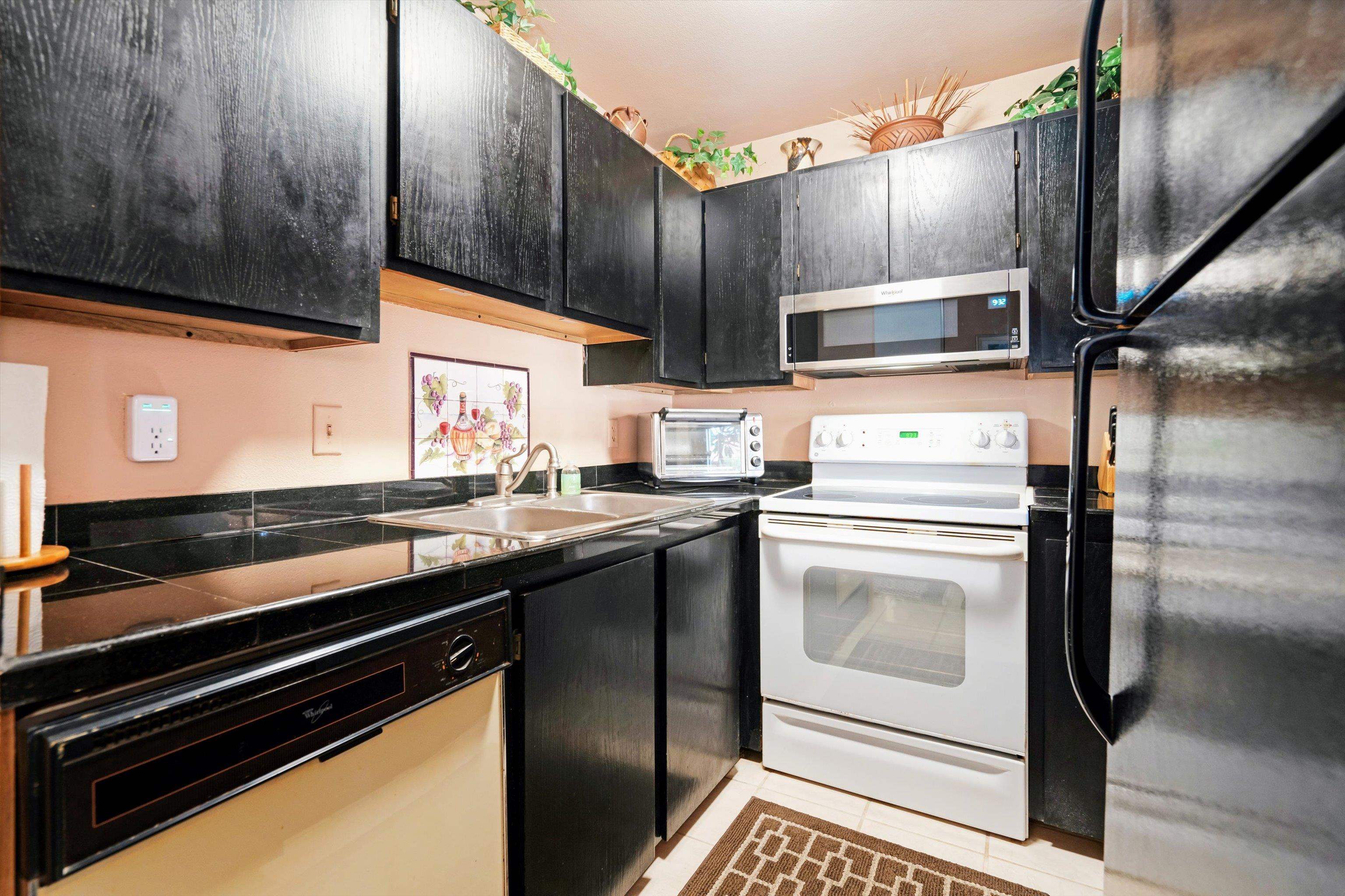 3740 Lower Honoapiilani Road, Unit C102 Lahaina, HI 96761 - Photo 12 of 50 a kitchen with stainless steel appliances kitchen island granite countertop a stove a refrigerator and cabinets