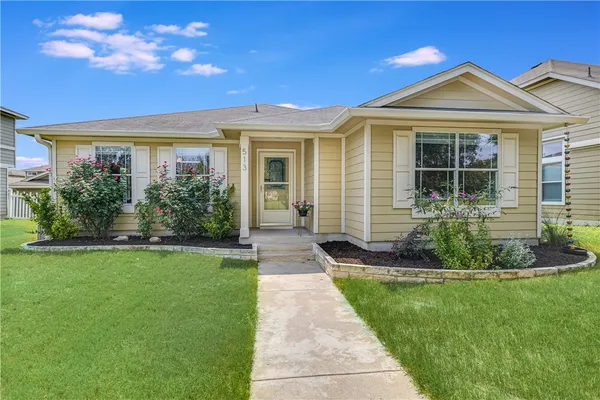 a front view of a house with a yard and potted plants