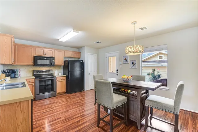 a kitchen with stainless steel appliances a dining table chairs stove and refrigerator