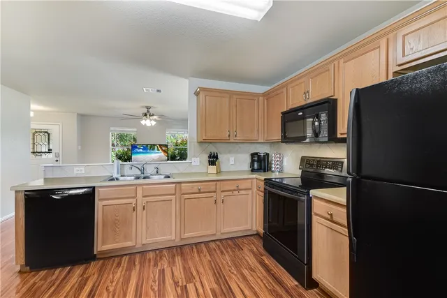 a kitchen with a sink dishwasher a refrigerator and cabinets with wooden floor