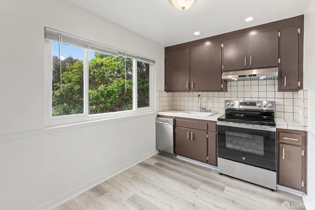 a kitchen with kitchen island granite countertop a sink cabinets and stainless steel appliances
