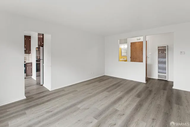 a view of an empty room with wooden floor and a window