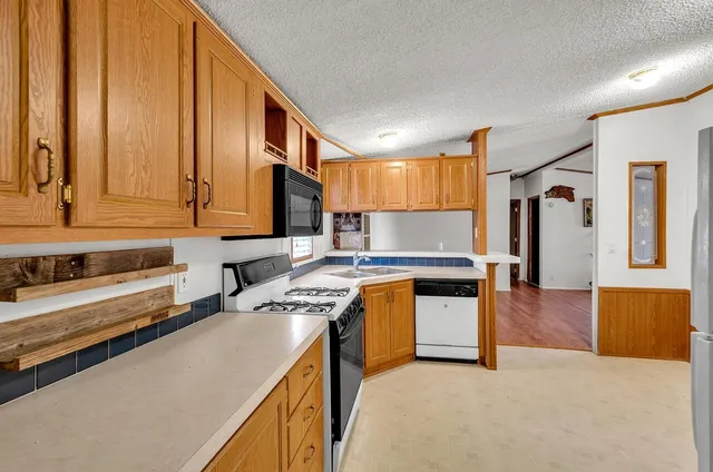 a kitchen with a refrigerator a stove top oven a sink dishwasher and white cabinets with wooden floor