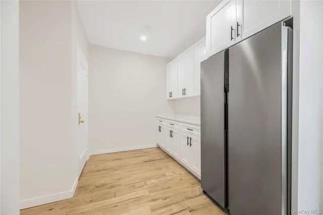 a view of a refrigerator in kitchen and white cabinets