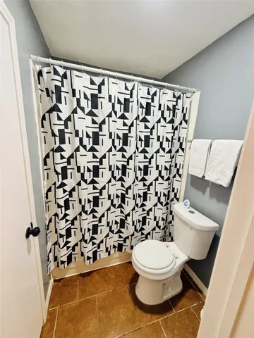 a bathroom with a toilet and a shower curtain