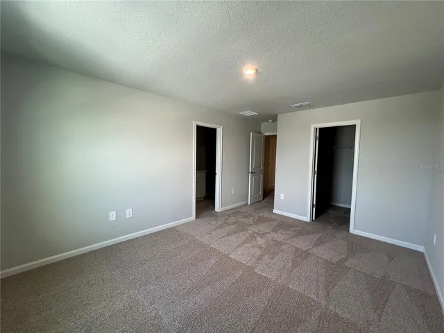 a view of an empty room with closet and entryway