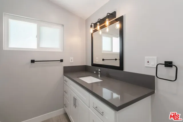 a bathroom with a granite countertop sink and a mirror
