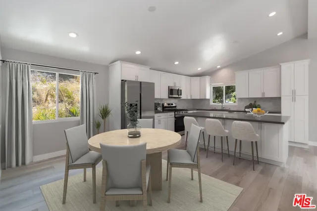 a kitchen with a dining table chairs refrigerator and wooden floor