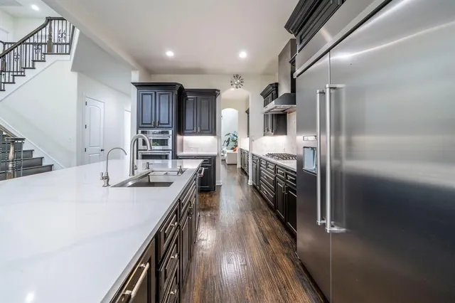 a kitchen with kitchen island a counter top space a sink stainless steel appliances and cabinets