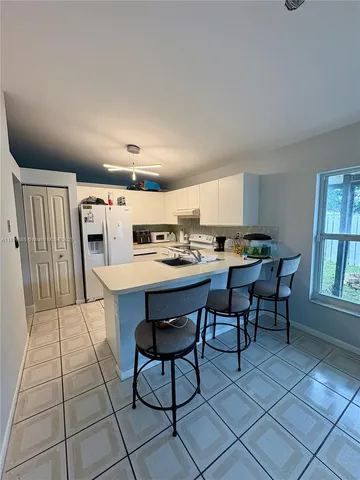 a open kitchen with stainless steel appliances a table chairs and a refrigerator