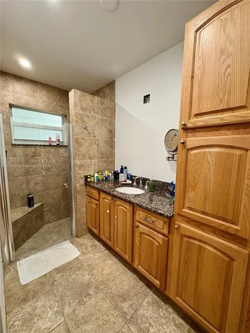 a bathroom with a granite countertop sink a mirror and a bathtub