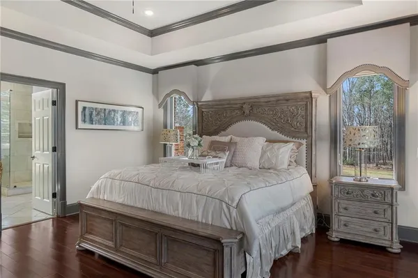 a bedroom with a bed a mirror on the dresser and a window