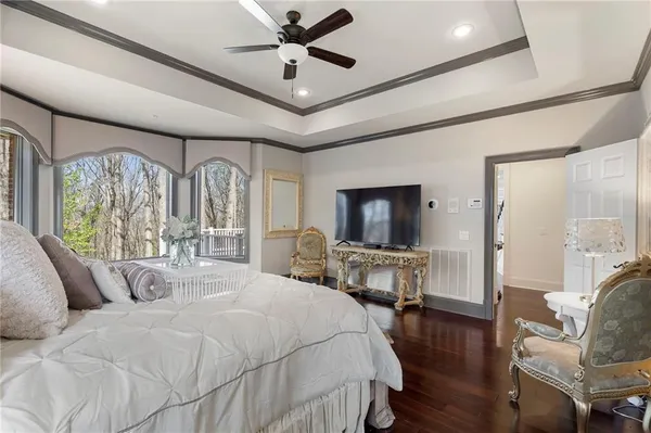 a spacious bedroom with a large bed a chandelier and windows