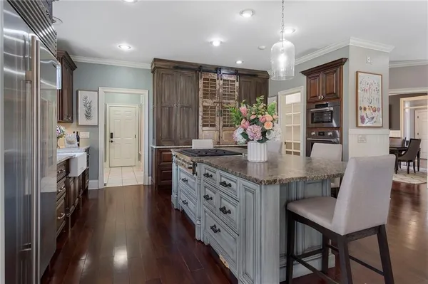 a kitchen with stainless steel appliances granite countertop a table chairs refrigerator and a sink