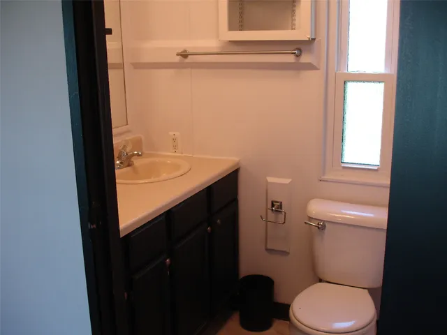 a bathroom with a granite countertop toilet and a sink