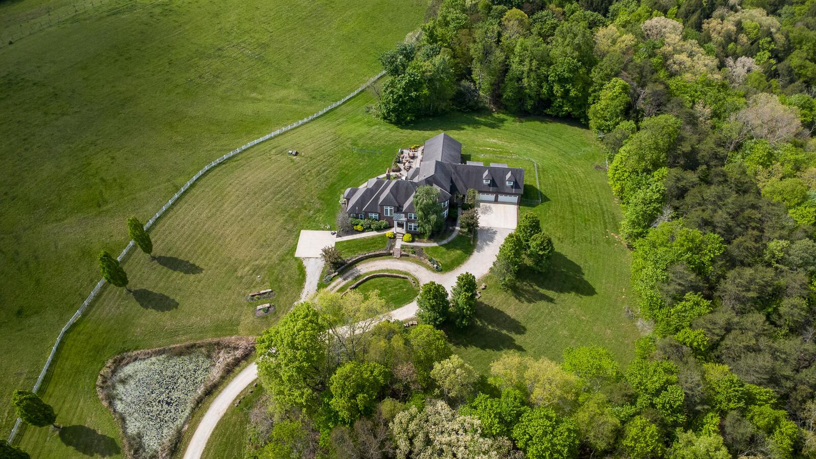 Stately brick estate surrounded by forest and meadows.