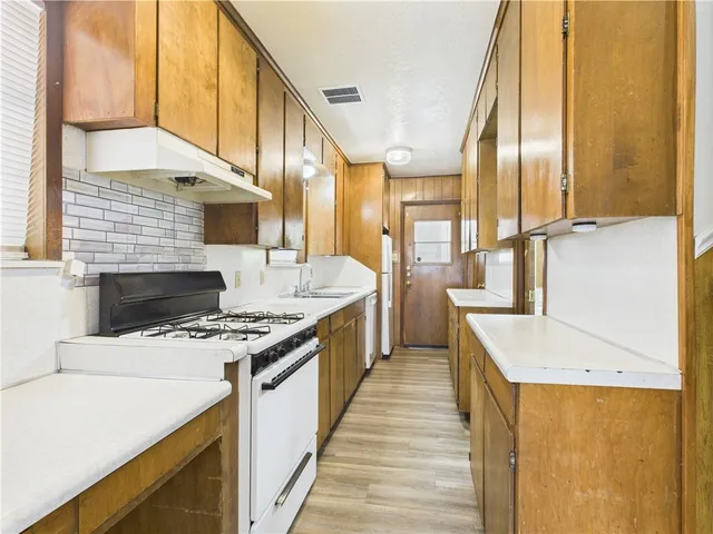 a kitchen with stainless steel appliances granite countertop a sink a stove and a refrigerator