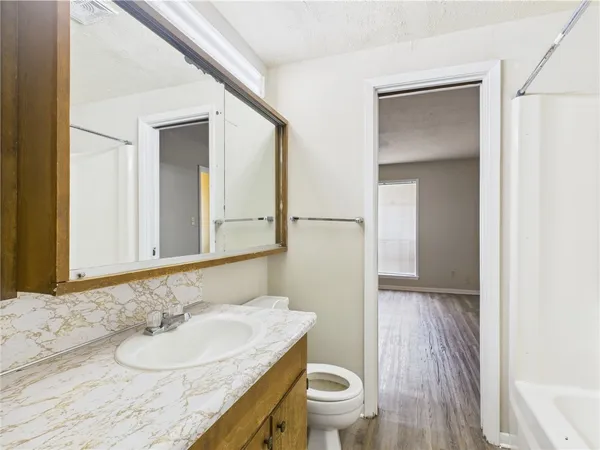 a bathroom with a granite countertop sink a toilet and a mirror