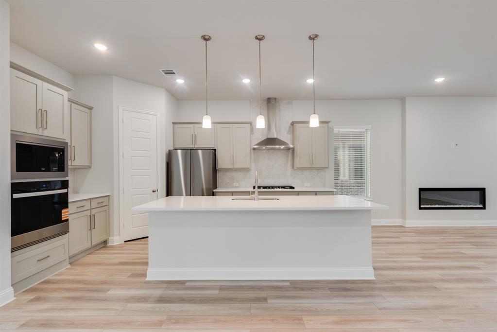 7009 Sunset Boulevard Rowlett, TX 75088 - Photo 8 of 35 a large kitchen with stainless steel appliances kitchen island a large counter top and a wooden floors