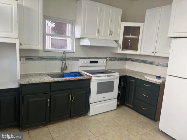 a kitchen with granite countertop a sink a stove and cabinets