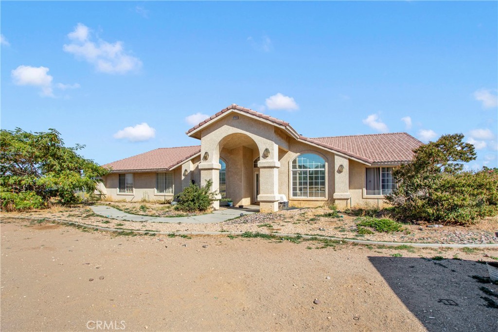 8755 Kittering Road Oak Hills, CA 92344 - Photo 1 of 1 a front view of a house with a dirt yard and a large tree