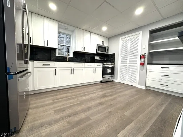 a kitchen with stainless steel appliances kitchen island granite countertop a refrigerator and cabinets