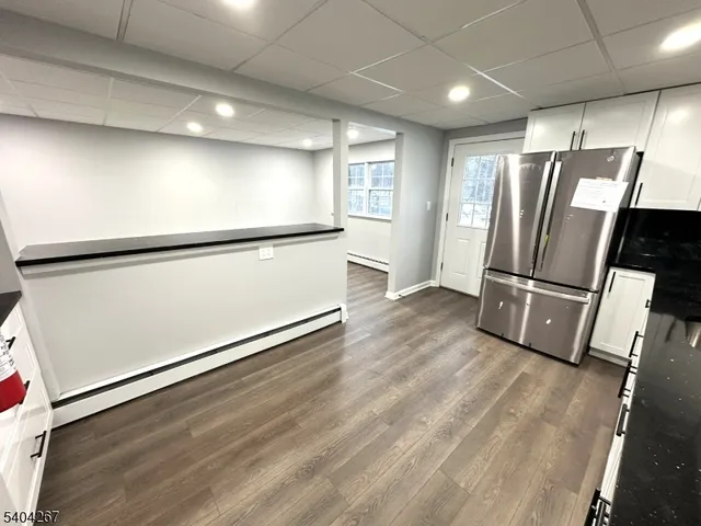 a view of an empty room with wooden floor and a refrigerator