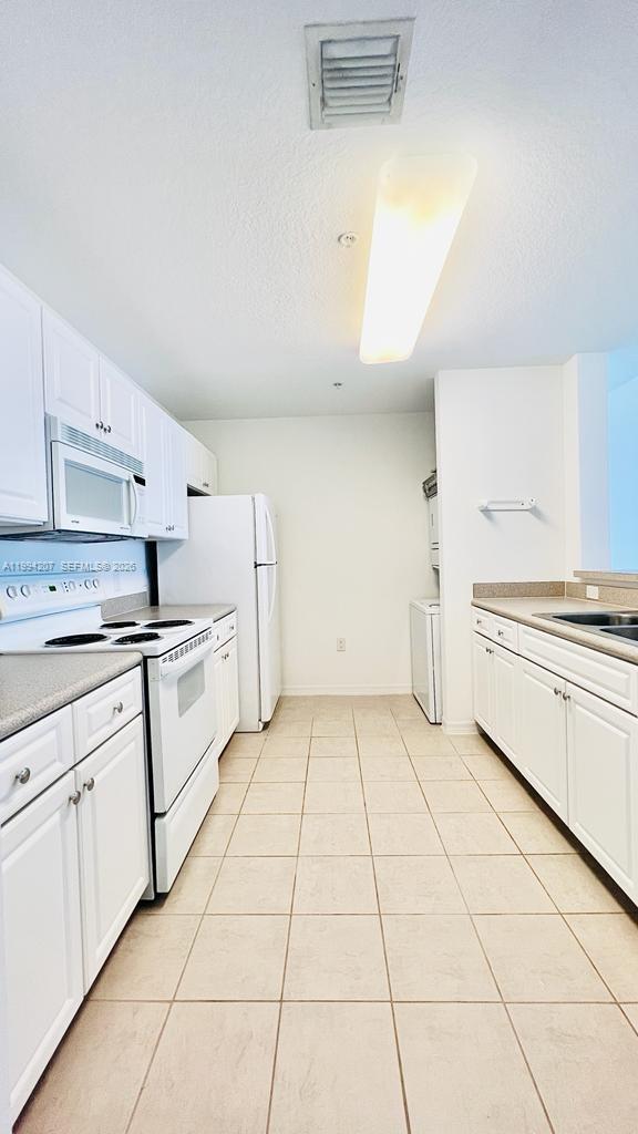 1209 Main Street, Unit 315 Jupiter, FL 33458 - Photo 9 of 18 a kitchen with white cabinets a sink and white appliances