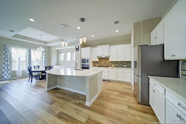 a view of kitchen with stainless steel appliances granite countertop a stove top oven a sink dishwasher a dining table and chairs with wooden floor