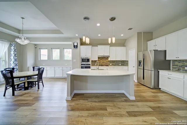 a large white kitchen with wooden floors and stainless steel appliances