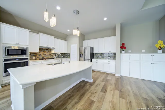 a large kitchen with stainless steel appliances lots of counter space and wooden floor