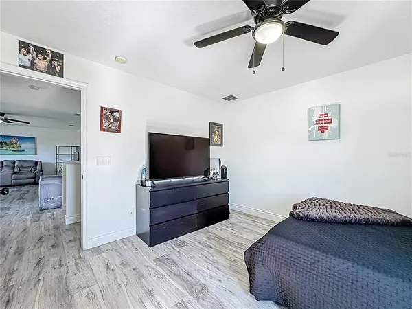 a living room with flat screen tv and a ceiling fan
