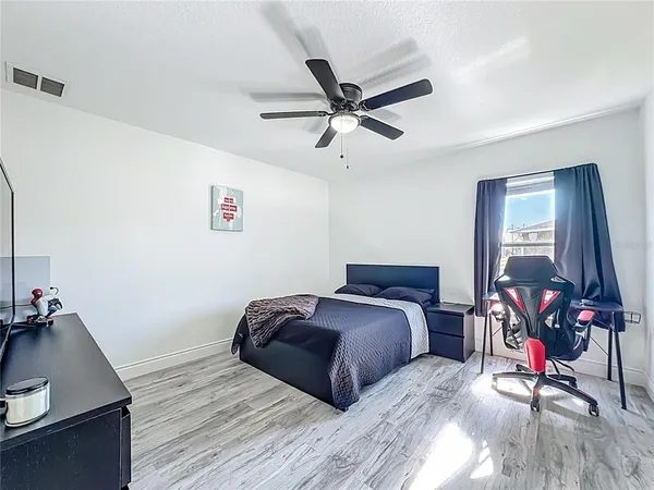 a spacious bedroom with a bed a couch and a flat screen tv