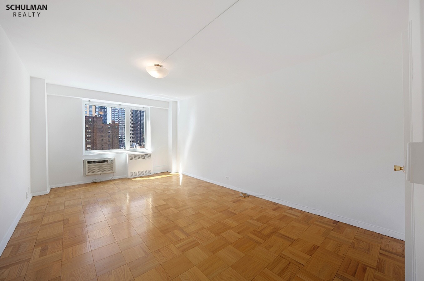 411 East 53rd Street, Unit 14F Manhattan, NY 10022 - Photo 10 of 20 a view of an empty room with a window and kitchen view