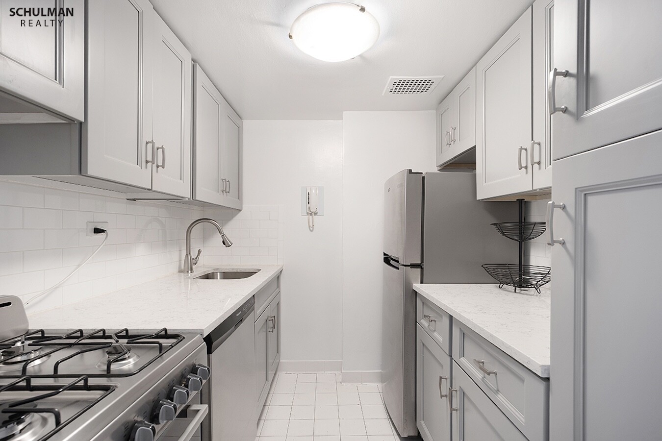 411 East 53rd Street, Unit 14F Manhattan, NY 10022 - Photo 12 of 20 a kitchen with stainless steel appliances a sink stove and refrigerator