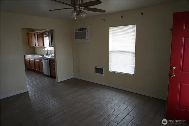 a view of an empty room with a window and wooden floor