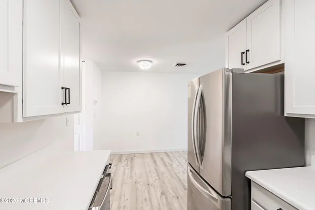 a view of a kitchen with refrigerator and wooden floor