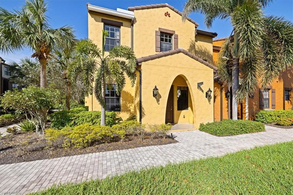 8997 Cambria Circle, Unit 201 Naples, FL 34113 - Photo 21 of 33 a view of a brick house with a small yard plants and palm trees