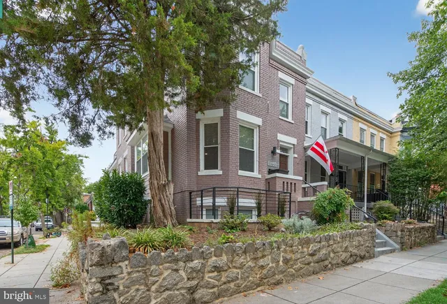 a front view of a multi story residential apartment building with yard and green space
