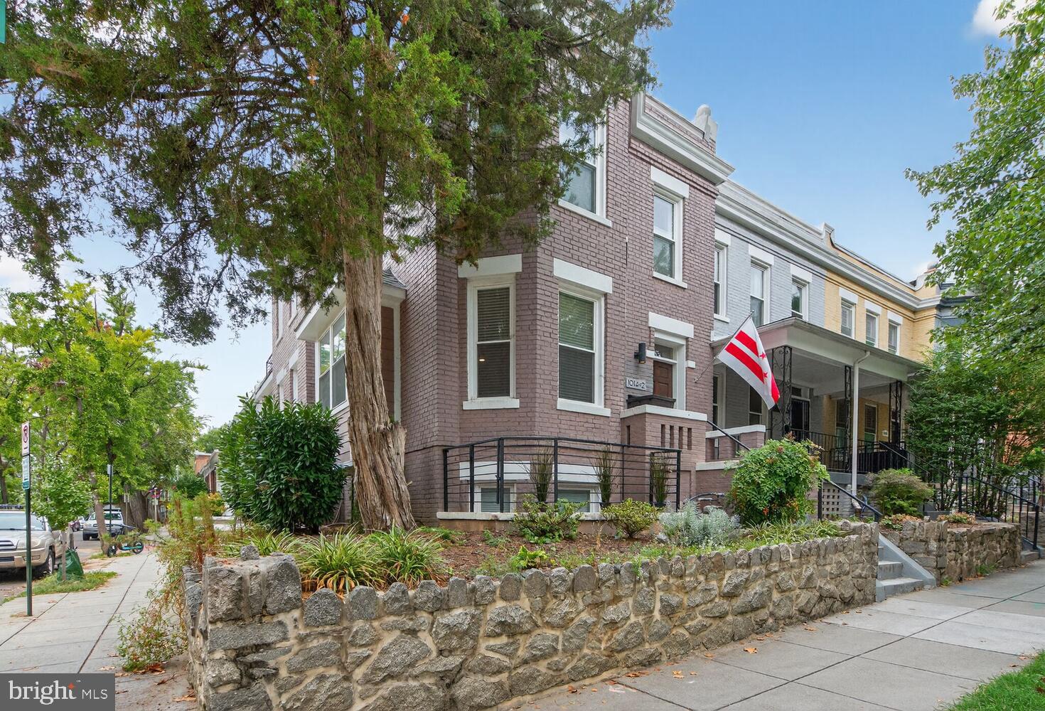 a front view of a multi story residential apartment building with yard and green space