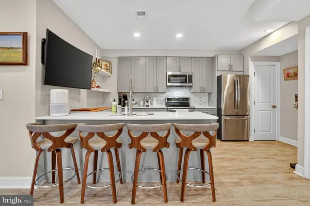 a kitchen with stainless steel appliances a microwave a stove a refrigerator and a dining table with wooden floor