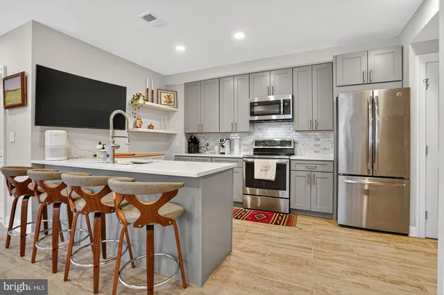 a kitchen with stainless steel appliances a stove a sink a refrigerator and a refrigerator