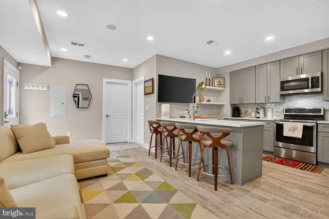 a living room with stainless steel appliances furniture and a flat screen tv