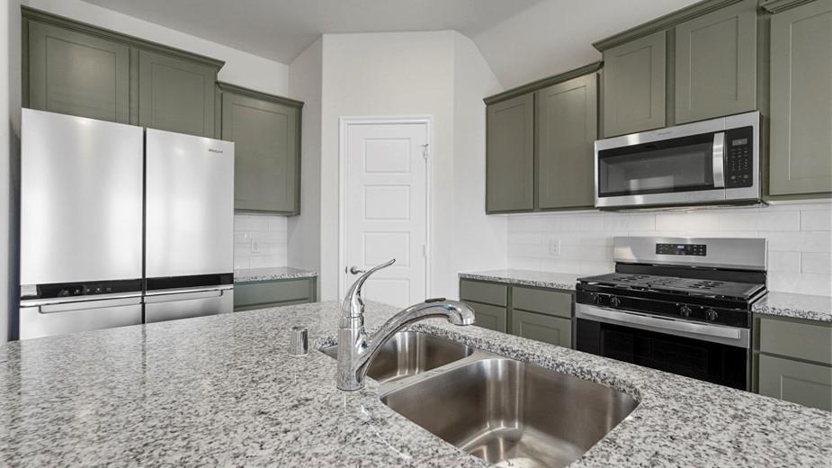 439 Epiphany Lane Lavon, TX 75166 - Photo 6 of 31 Kitchen featuring a double basin stainless steel sink, chrome faucet, granite countertops, sage cabinetry, and stainless steel appliances including a side-by-side refrigerator, microwave, and gas range