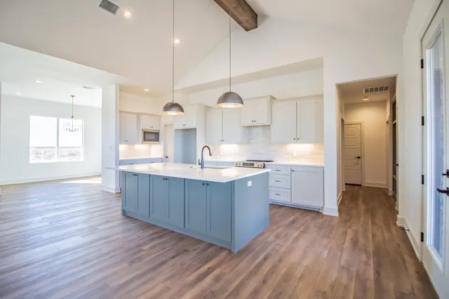 an empty room with wooden floor fireplace and windows