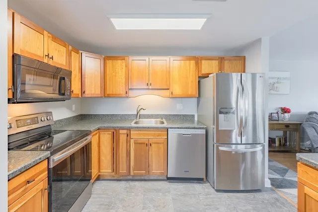 a kitchen with stainless steel appliances granite countertop a refrigerator a stove a sink and a microwave