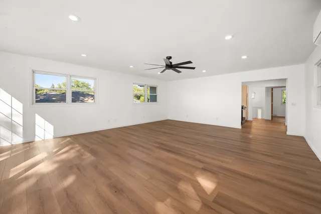 a view of empty room with wooden floor and fan