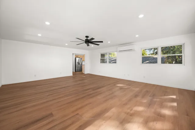 a view of empty room with wooden floor and fan