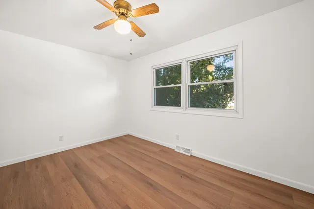 an empty room with a window and a fan