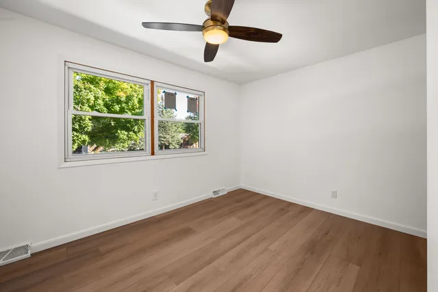 a view of empty room with wooden floor and fan